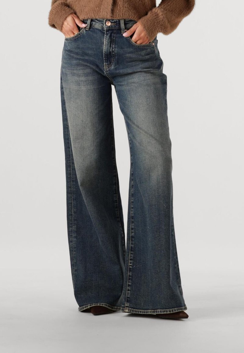 Wijduitlopende jeans van blauwe denim, met een hoge taille, lichte vervaging, voorzakken en een onafgewerkte zoom. Draag je met bruine schoenen.