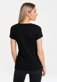 Black short-sleeved t-shirt with a fitted design, round neckline, and smooth cotton fabric, seen from the back against a light background.