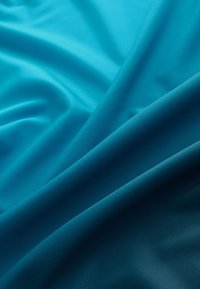 Türkiisriidest kangas, millel on sile tekstuur ja mitu volditud kihti, mis loovad pehme välimuse ning rikkaliku värvigradient.