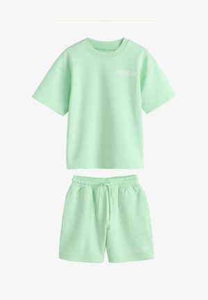 Myntegrøn T-shirt med korte ærmer med teksten "Palm Beach" og matchende shorts med snøre, vist mod en hvid baggrund.