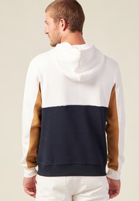 Felpa con cappuccio caratterizzata da un design color block in bianco, blu navy e marrone. Realizzata in tessuto morbido, con tasca a marsupio e polsini a costine.