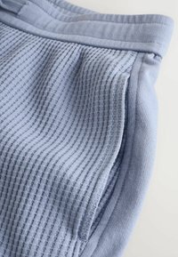 Lichtblauwe korte broek met een geribbelde textuur, voorzien van een elastische tailleband en een glad, vlak gedeelte. Geen zichtbare hardware of patronen.
