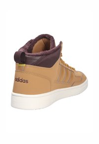 Brązowe wysokie trampki z sztucznym futerkiem na kołnierzu, sznurówkami i białą podeszwą. Posiadają trzy paski w wzorze oraz haftowane logo na pięcie.