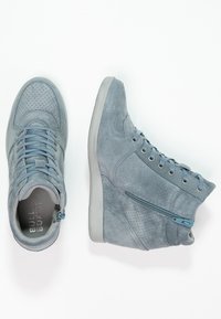 High-top sneakers in light blue suede with perforated accents, flat laces, and a side zipper. Rubber sole with a slightly elevated heel.