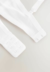 Vita justerbara bh-remmar i slät tyg, med ett texturerat område för hänge och en sömlös design.