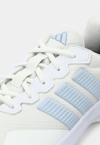 Λευκό και ανοιχτό μπλε παπούτσι Adidas με υφασμάτινο διχτυωτό, κλείσιμο με κορδόνια, τρεις ανάγλυφες πλευρικές ρίγες και λογότυπο στη γλώσσα.