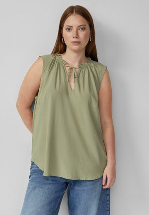 Haut sans manches vert olive avec un col froncé et un détail en trou de serrure, fabriqué dans un tissu lisse, associé à un jean en denim bleu clair.