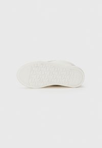 Hvit gummisåle til sneakers med en strukturert overflate, med et sekskantet mønster og en lett heving ved hælen.