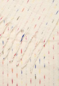 Hvid tekstil med farverige lodrette striber i pink, blå, gul og grå. Flossede kanter giver en tekstureret overflade. Blødt, let materiale.