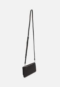 Svart skinn crossover veske med rektangulær form, glidelås, justerbar stropp og minimalistisk design. Jevn tekstur, ingen mønstre.