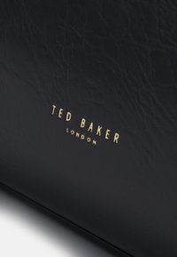 Svart texturerad läderväska med framträdande guld "TED BAKER LONDON" logotyp. Slät yta med subtila veck. Rektangulär form.