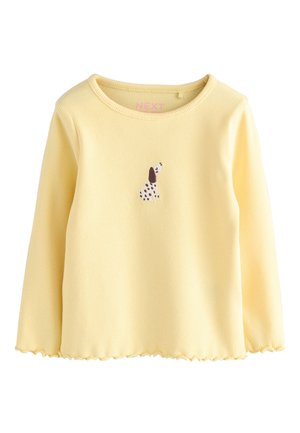 Gul ribbet langærmet top med en bølget kant og et lille broderet hundemotiv på forsiden. Fremstillet af blødt bomuldsstof.