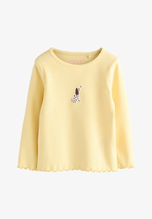 Kollane soonikkoes pika varrukaga pluus lameda lainelise servaga ja väikese tikitud koera kujundusega ees. Valmistatud pehmest puuvillamaterjalist.