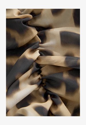 Kerge pehme võrkkangas beežis, millel on ebaühtlased mustad laigud. Kogutud tekstuur lisab sügavust, luues kihilise ja pehme väljanägemise.