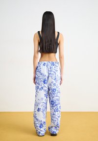 Lösa byxor i blått och vitt blommönster; elastisk midja, lätt tyg och något skrynklig textur. Svart tajt topp.