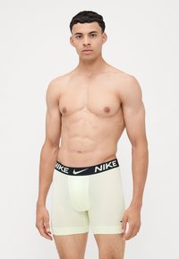Svetlozelené boxerky Nike s čiernym elastickým pásom, na ktorom je v bielej farbe nápis "NIKE". Hladká textúra a priliehavý strih.