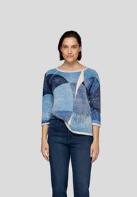 Blauer und cremefarbener Pullover mit einem geometrischen Color-Blocking-Muster in verschiedenen Blautönen, mit Dreiviertelärmeln und einem abgerundeten Saum.