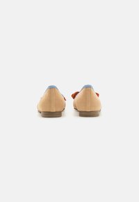 Pantofi din suede bej cu un accent albastru la călcâi și un detaliu sub formă de fundă portocalie pe lateral. Talpă plată, design cu vârf rotund.