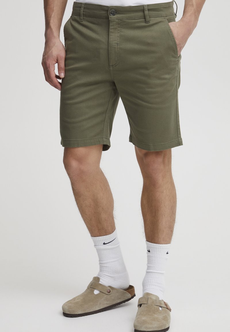 Olivengrønne shorts med rette ben, lavet af bomuld, med knaplukning i taljen, sidelommer og en enkel kant.
