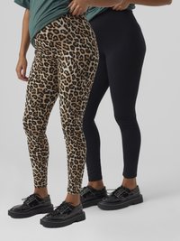 Trikot-Leggings im Leopardenmuster und einfarbig schwarz, gefertigt aus dehnbarem Material. Beide kombiniert mit schwarzen Plateau-Schuhen.