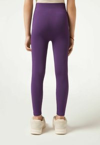 Paarse ribgebreide leggings met een hoge tailleband, een gladde textuur en een aansluitend ontwerp, gecombineerd met beige sportschoenen.