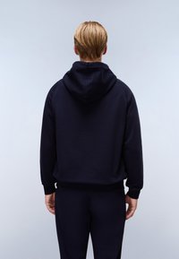 Hanorac bleu marin cu glugă, cu manșete și talie ribbate. Textură netedă și croială lejeră, completat cu pantaloni întunecați asortați.