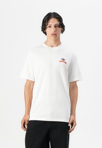 White cotton T-shirt featuring a round neck, short sleeves, and a small orange and burgundy logo on the left chest.