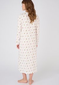 Lunga camicia da notte bianca con motivi floreali pastello e raggi di sole. Realizzata in tessuto morbido, presenta maniche lunghe e scollatura rotonda.