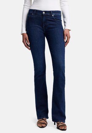 Jean en denim bleu foncé, évasés avec une taille mi-haute, présentant une braguette avec fermeture à bouton et des poches avant. Texture lisse et détails cousus.
