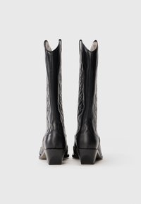 Stivali da cowboy in pelle nera con cuciture decorative e tacco basso, dotati di punte affusolate e un'apertura superiore leggermente svasata.