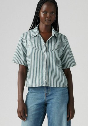 Striped short-sleeve button-up shirt in teal and white, with two front pockets and a pointed collar, featuring a cropped silhouette and soft texture.