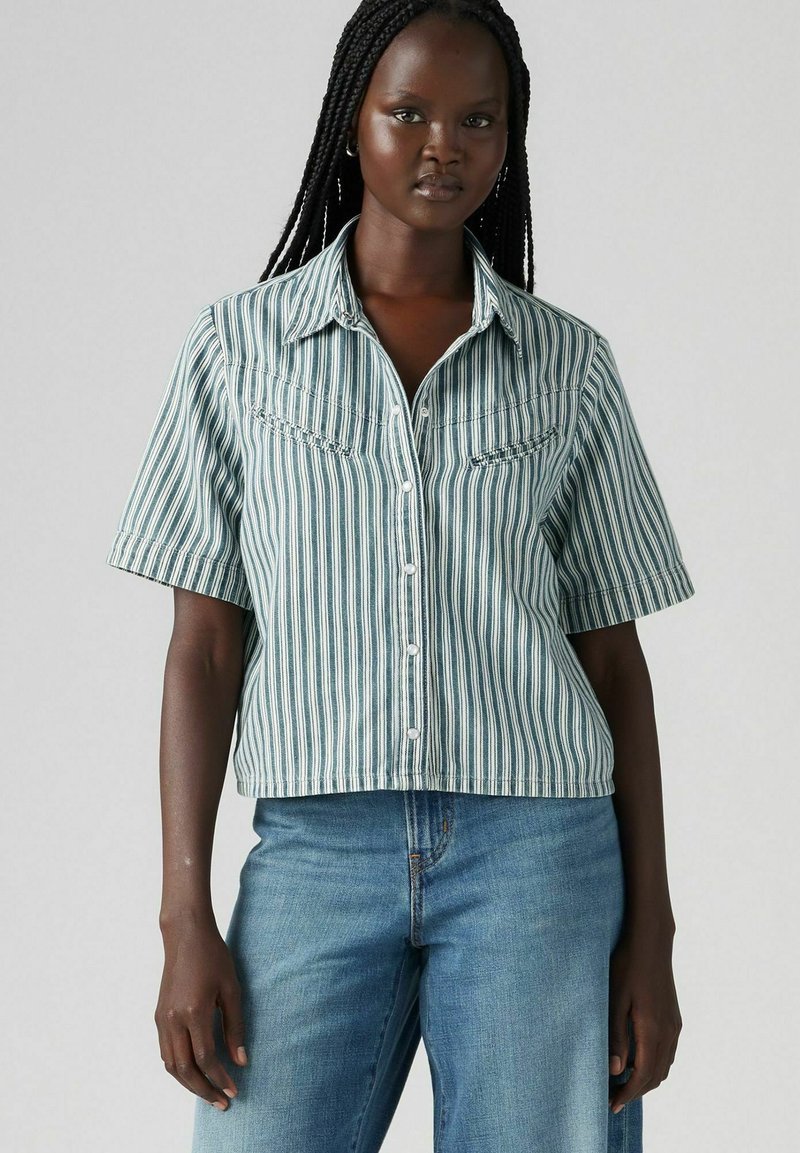 Camicia a maniche corte a righe in turchese e bianco, con due tasche frontali e colletto a punta, caratterizzata da una silhouette corta e una texture morbida.