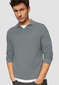 Hellgrauer, strukturierter Pullover mit V-Ausschnitt und kurzem Kragen. Mit gerippten Bündchen und Saum, über einem weißen Hemd getragen. Lässige Passform.