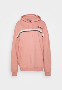 Sudadera rosa con un bolsillo frontal, capucha con cordón y acentos a rayas en crema y azul marino. Presenta un logo de 'Kickers' en el pecho.