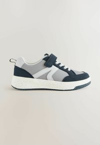 Baskets légères avec un design gris et marine, dotées d'une sangle en velcro, de lacets traditionnels et d'une semelle blanche tachetée.