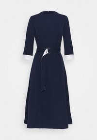 Dunkelblaues Midikleid mit Rundhalsausschnitt, Dreiviertelärmeln, weißen Manschetten und einem Stoffgürtel mit einer runden Schnalle. Glatte Textur.