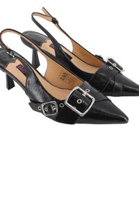 Tacones en charol negro tipo slingback con punta afilada, detalles de hebilla plateada y un tacón bajo y cuadrado.