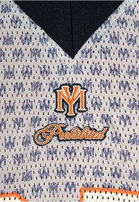 Primer plano de una camiseta deportiva gris perforada con un patrón repetido "NY", un logo bordado en naranja y negro con las letras "NY" y el texto "Prostandard" debajo.