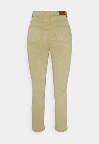 Pantalons droite taille haute beige avec poches arrière et un patch en cuir marron de la marque sur la ceinture.