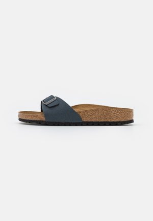 Niebieska klapka Birkenstock z korkową wkładką, czarnym regulowanym paskiem i czarną gumową podeszwą, pokazana z boku na białym tle.