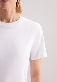 Wit, kortärmelig T-shirt gemaakt van zachte stof met een ronde halslijn en een gladde textuur, voorzien van een klassiek, eenvoudig ontwerp.