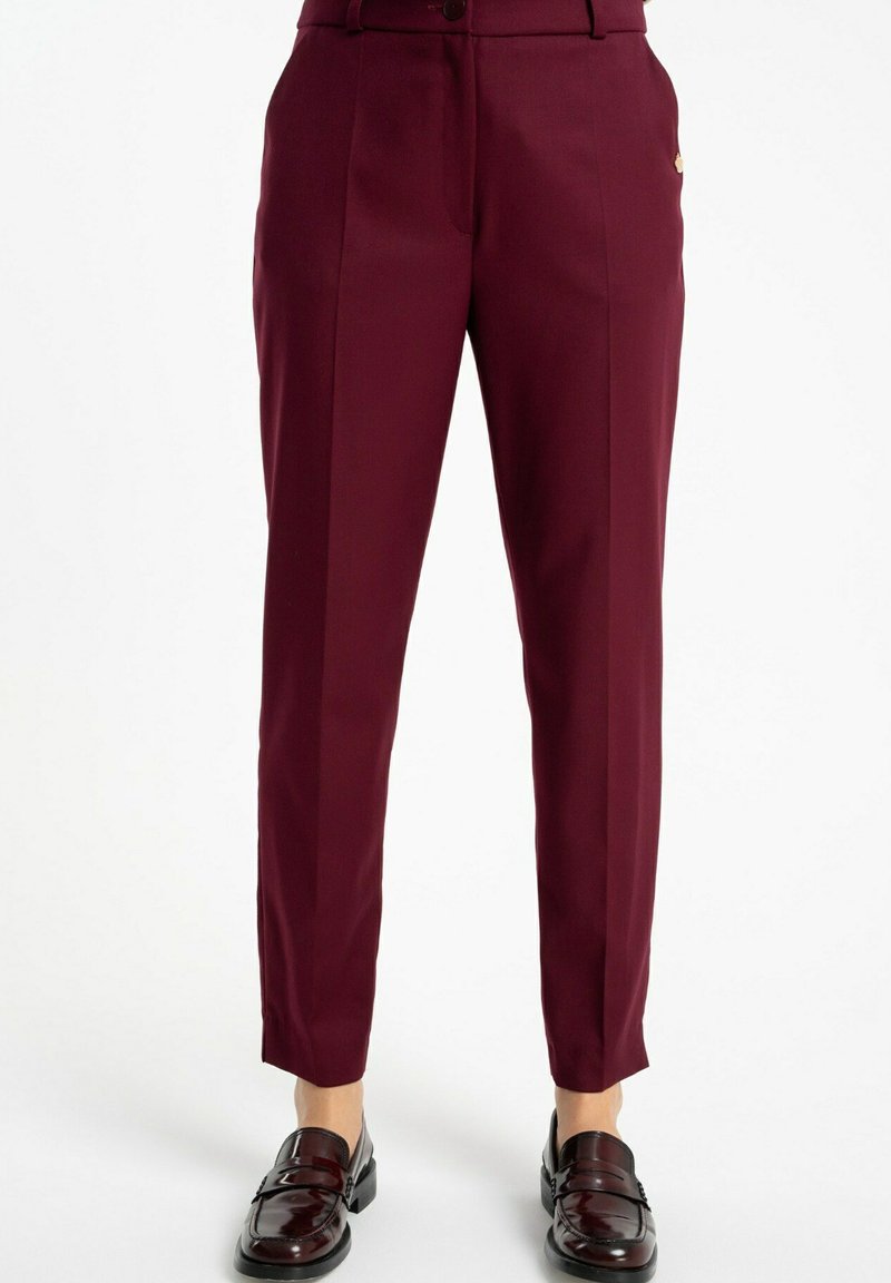 Bordowe dopasowane spodnie z przodu, z kieszeniami bocznymi i subtelnym akcentem logo. Gładka faktura materiału.