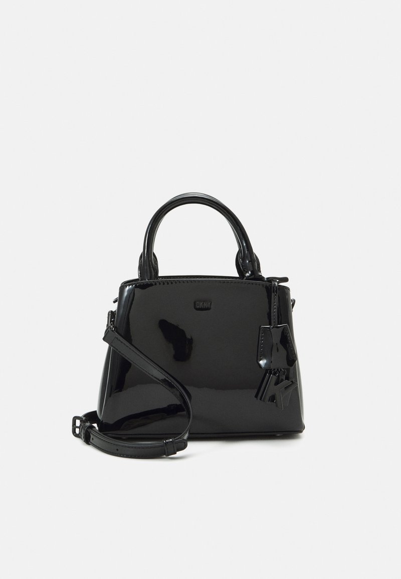 Black patent leather handbag with a structured shape, dual top handles, and a detachable shoulder strap. Features a branded metal charm.