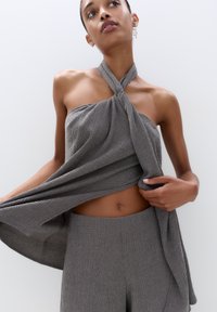 Gray textured two-piece outfit featuring a strapless top tied at the neck and wide-leg trousers. Smooth fabric with a subtle pattern.
