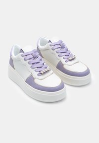 Bijele i lavanda platformske tenisice s elegantnim dizajnom, ljubičastim vezicama i dekorativnim srebrnim detaljem na jeziku.