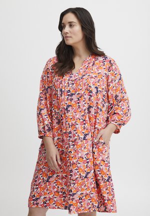 Blommig knälång klänning i rosa med mönster i orange, lila och vitt. Har en V-ringning, avslappnade ärmar och sidofickor.