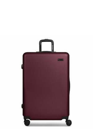 Donkere rode koffer met harde schaal, telescopisch handvat en vier zwarte zwenkwielen, voorzien van een klein rechthoekig label aan de voorkant.