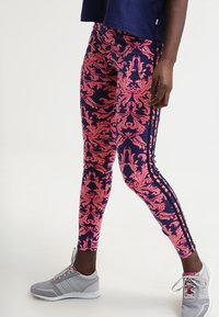 Legíny v námořnické modři s růžovým zdobeným květinovým vzorem, s černými pruhy na bocích. Kombinované se šedými sportovními botami. Měkká, elastická tkanina.