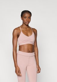 Ανοιχτό ροζ αθλητικό σουτιέν με ραβδώσεις, λεπτές τιράντες και άνετη εφαρμογή, σε συνδυασμό με αντίστοιχο ψηλόμεσο κολάν.