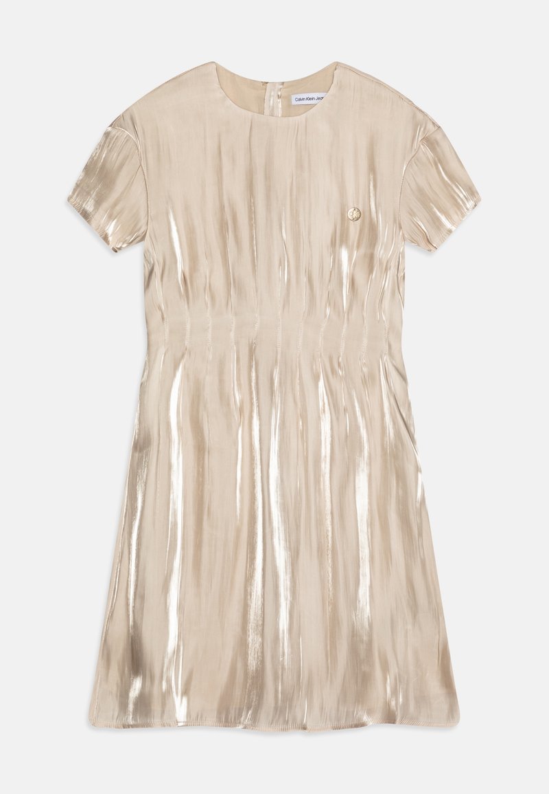 Robe beige brillante à manches courtes avec encolure ronde et petit emblème rond sur la poitrine, étalée à plat sur un fond blanc.
